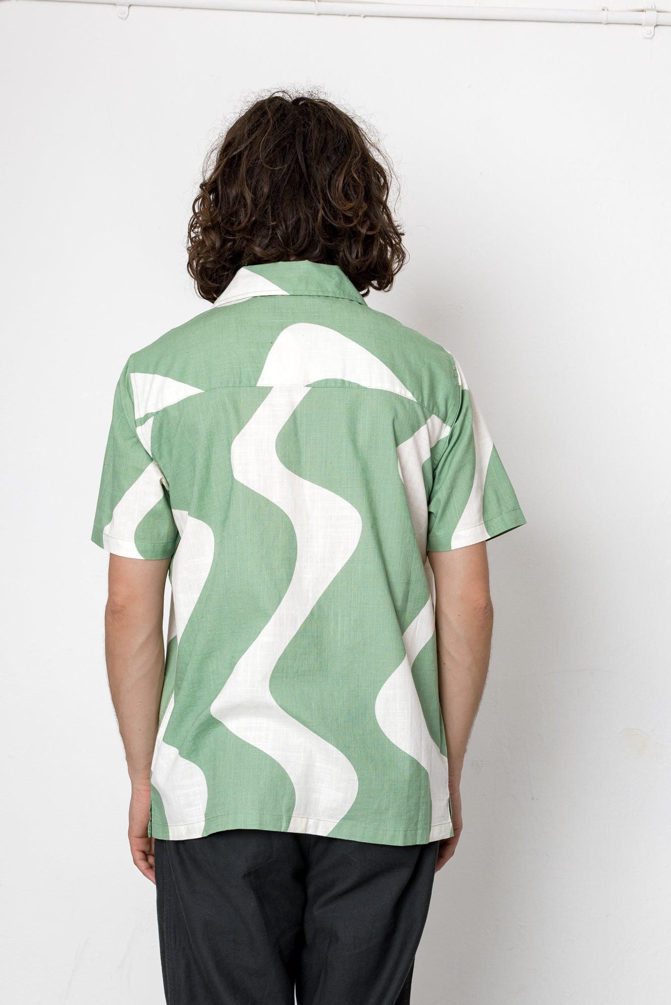 Person wearing a green and white patterned shirt against a white background