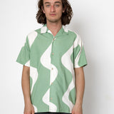 Man wearing a green and white patterned shirt against a white background