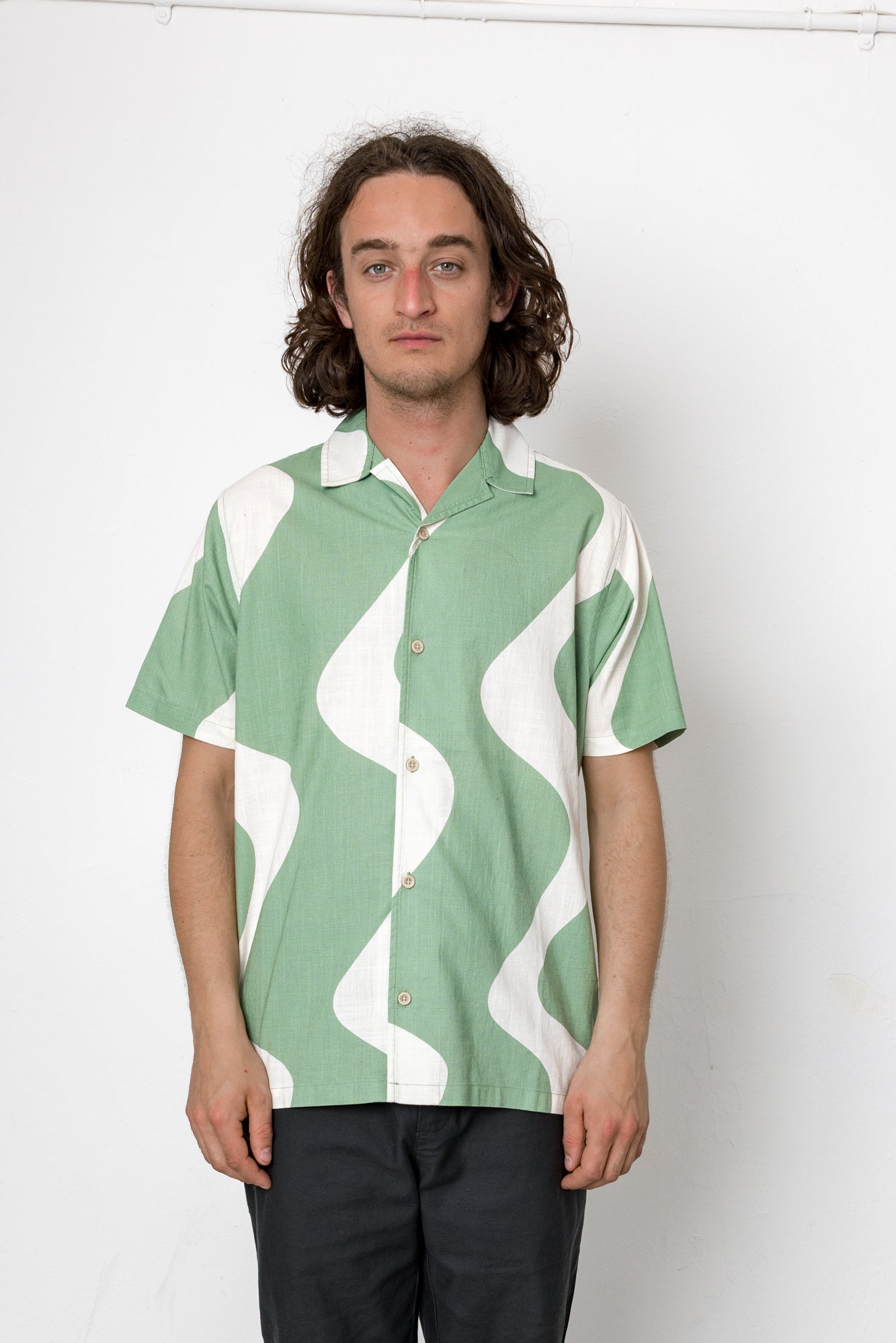 Man wearing a green and white patterned shirt against a white background