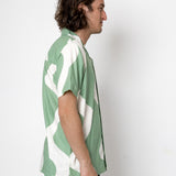 Man wearing a green and white patterned shirt against a white background
