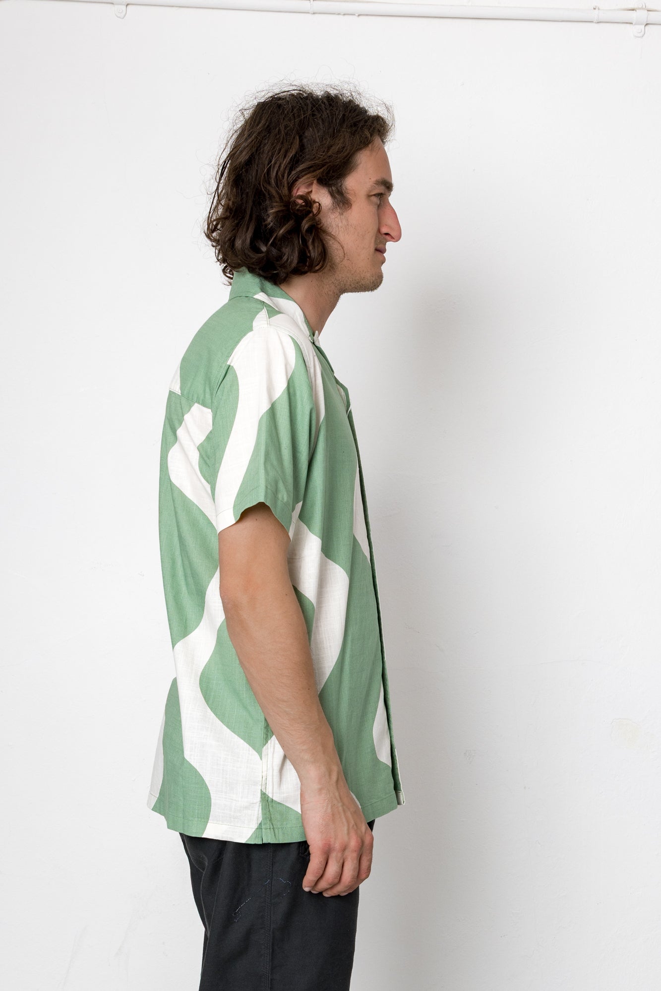 Man wearing a green and white patterned shirt against a white background