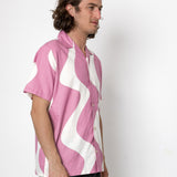 Man wearing a pink and white patterned shirt against a white background