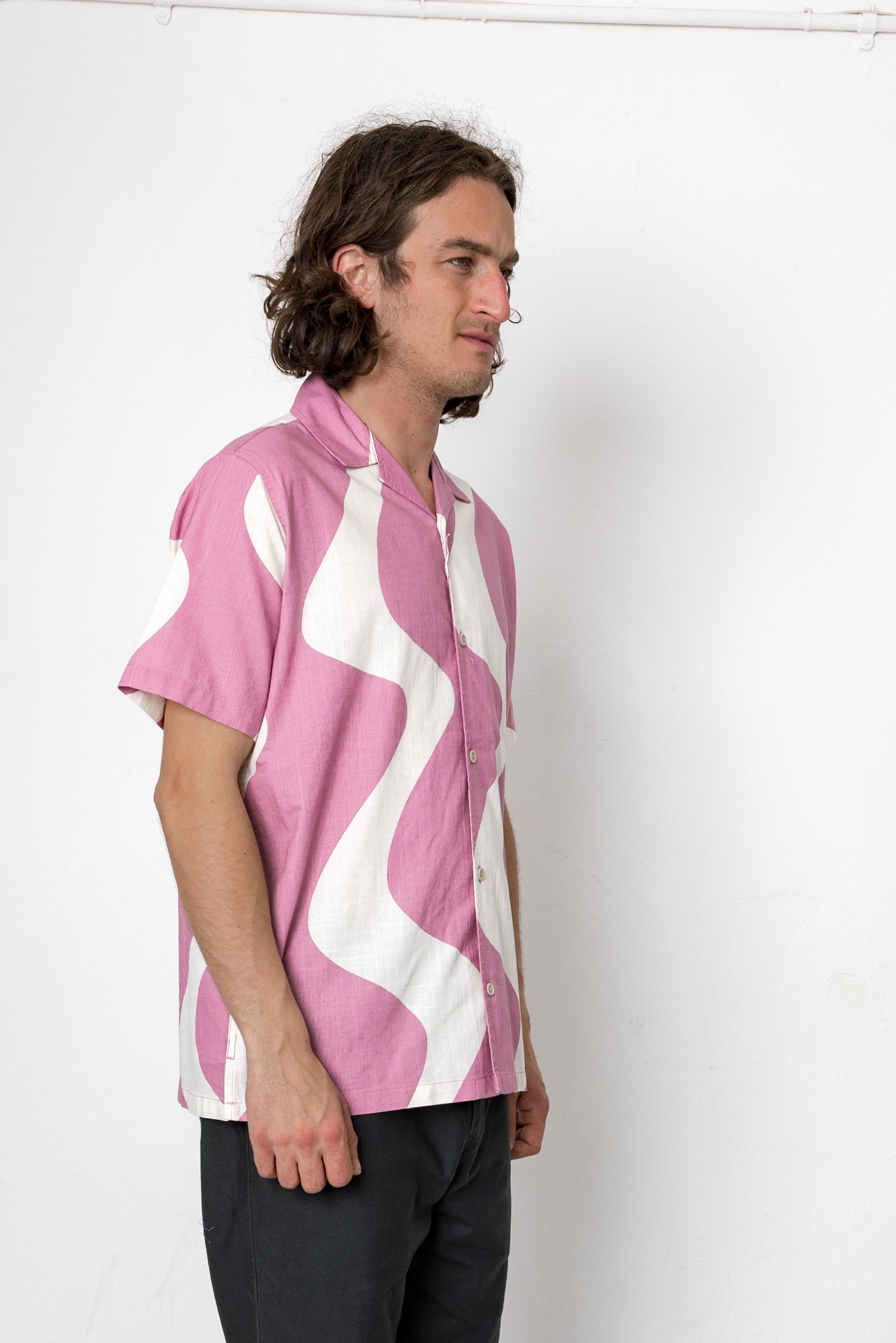 Man wearing a pink and white patterned shirt against a white background