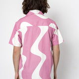 Person wearing a pink and white patterned shirt on a plain background