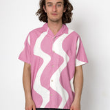 Person wearing a pink shirt with white wavy pattern on a white background