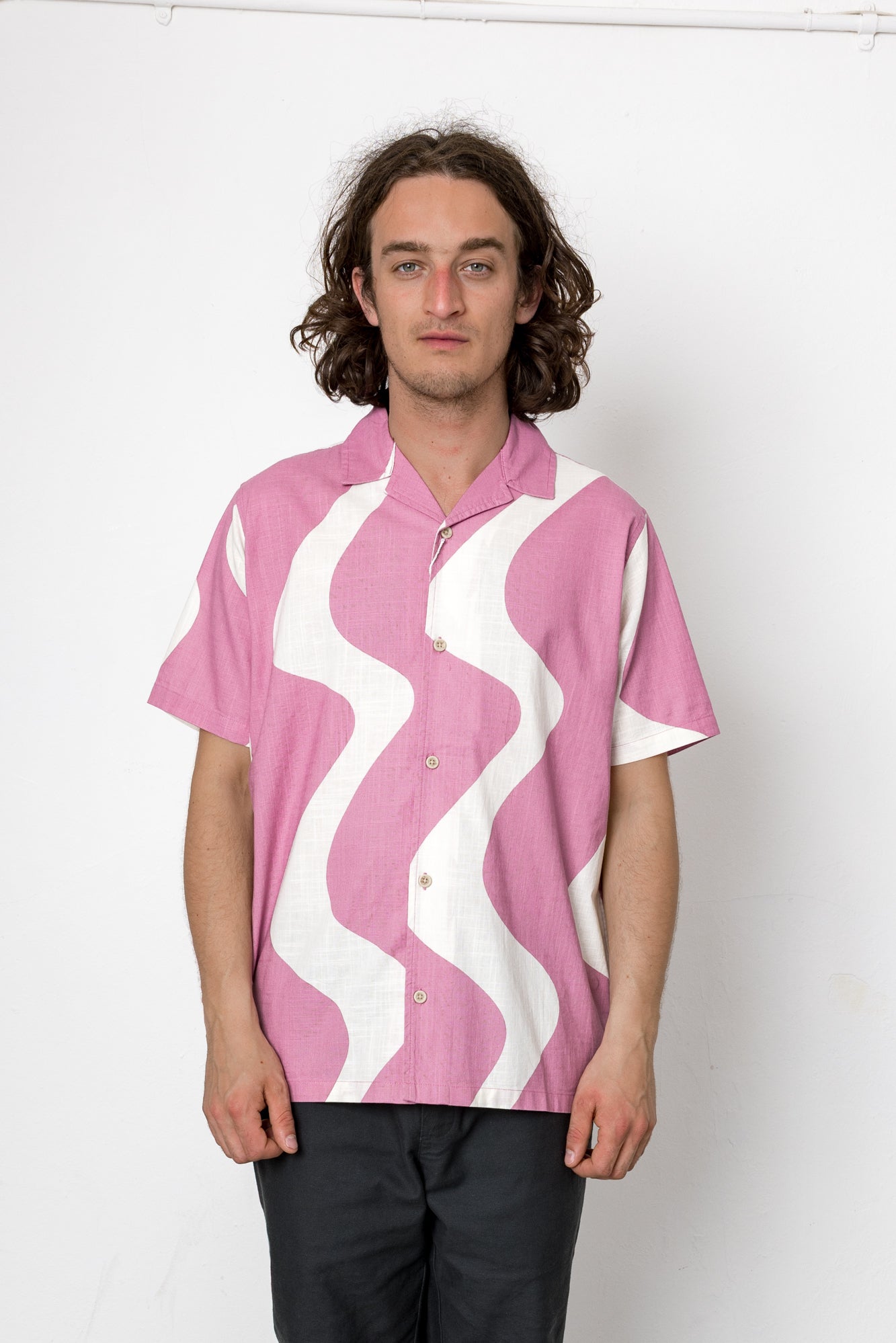 Person wearing a pink shirt with white wavy pattern on a white background