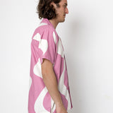 Person wearing a pink and white patterned shirt against a white background