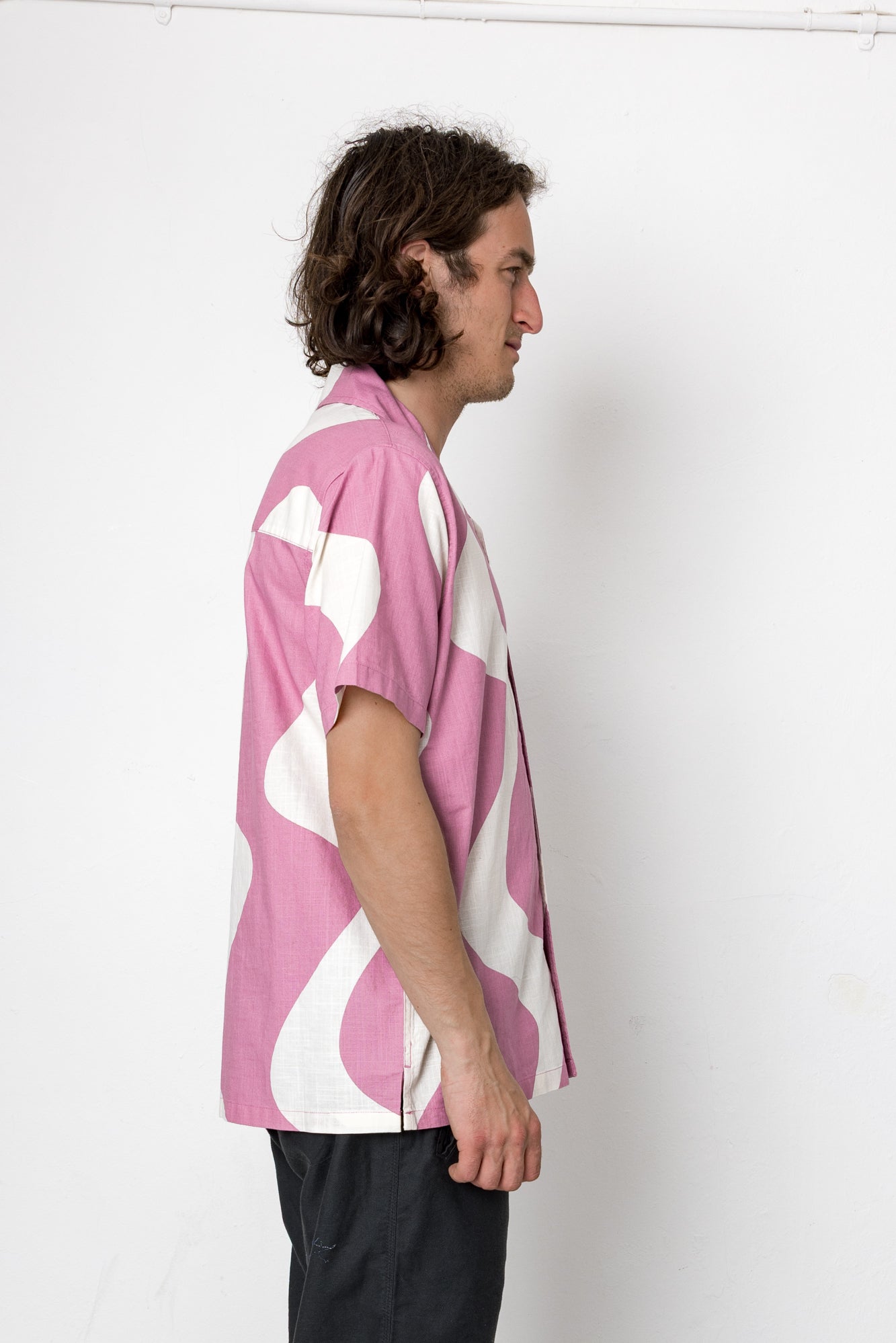 Person wearing a pink and white patterned shirt against a white background