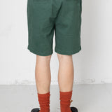 Person wearing green shorts and red socks with black shoes on a white background