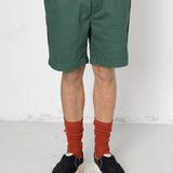 Person wearing green shorts, red socks, and black shoes on a white background