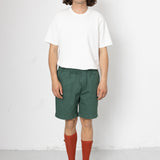 Person wearing a white t-shirt, green shorts, and red socks on a white background