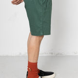 Person wearing green shorts, black shoes, and orange socks on a white background