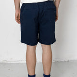 Person wearing navy shorts and black sneakers on a white background