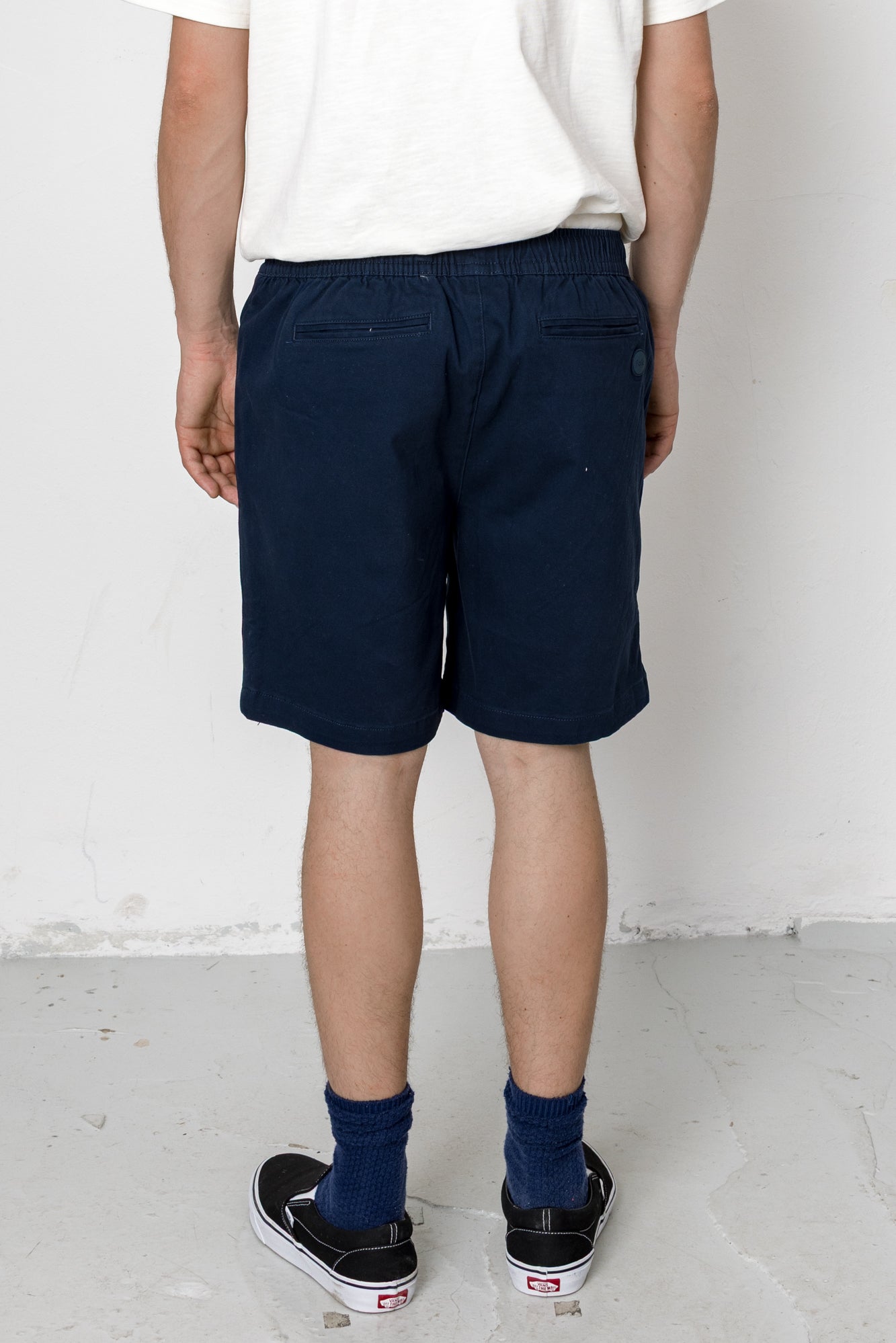 Person wearing navy shorts and black sneakers on a white background