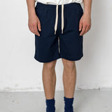 Person wearing navy shorts with a white background