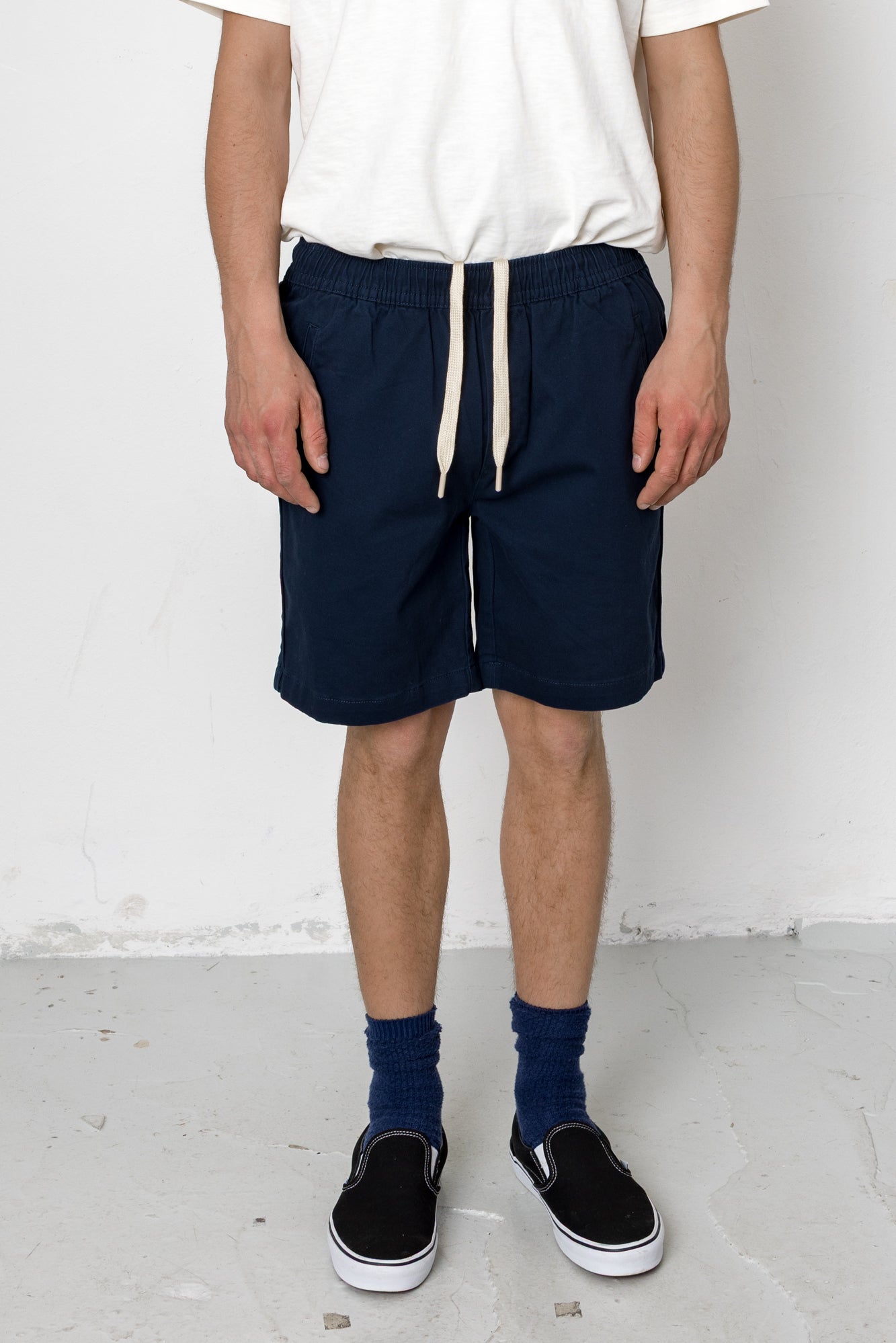 Person wearing navy shorts with a white background