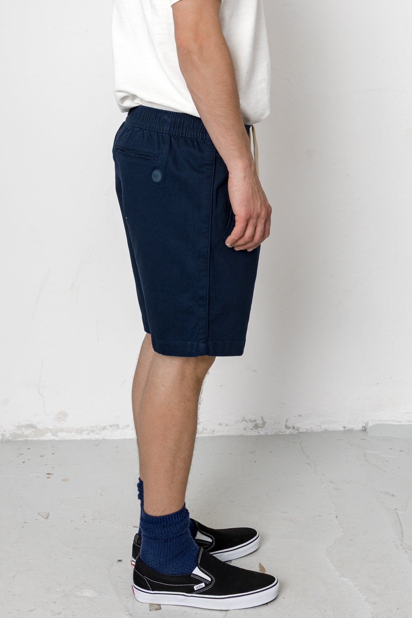 Person wearing navy shorts and black sneakers on a white background