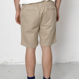 Person wearing beige shorts and navy socks with black shoes on a white background