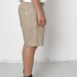 Person wearing beige shorts and black sneakers on a white background