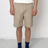 Person wearing beige shorts, white t-shirt, and black shoes on a plain background