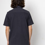 Person wearing a black polo shirt against a white background