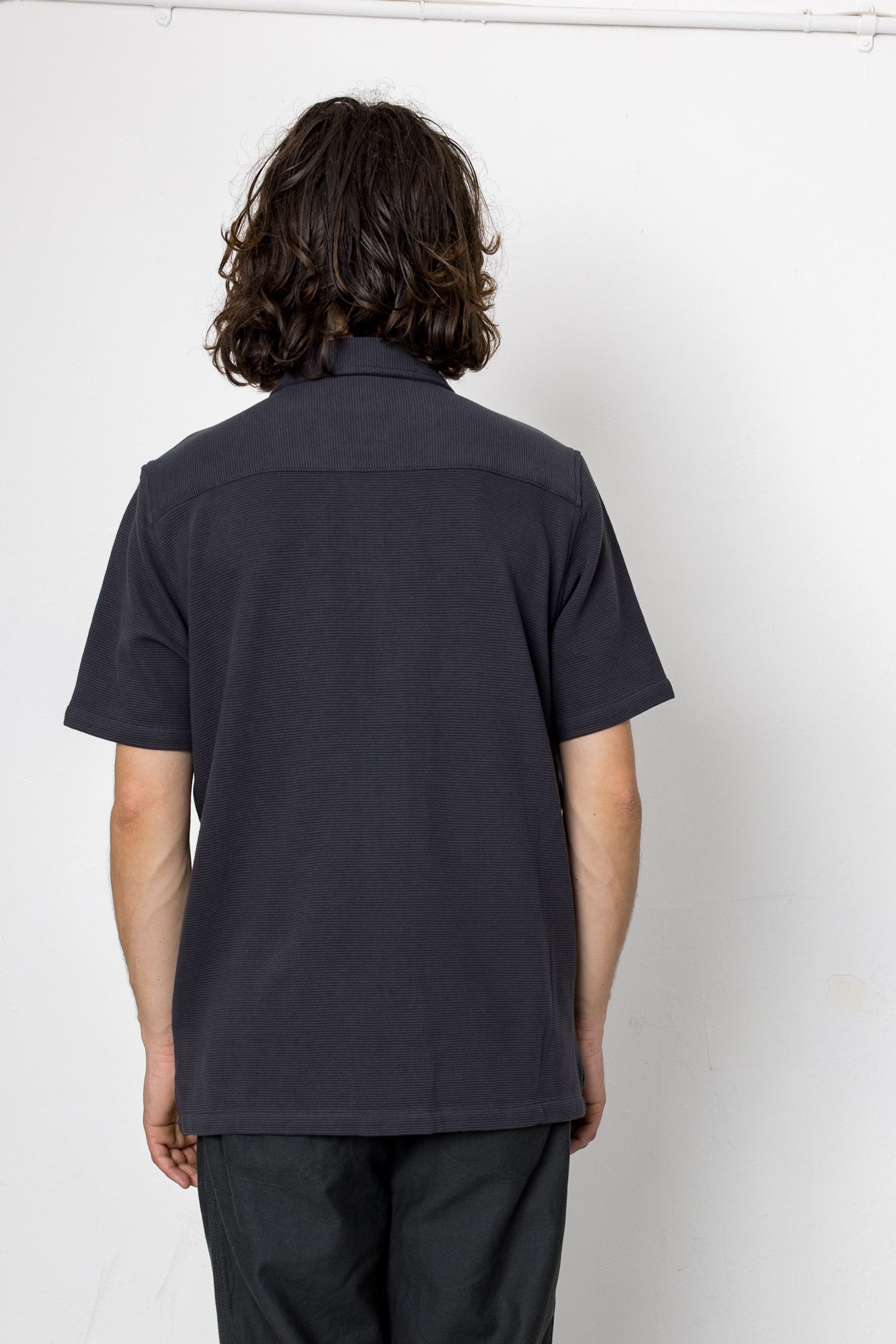 Person wearing a black polo shirt against a white background