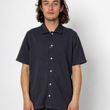 Man wearing a navy short-sleeve button-up shirt against a white background