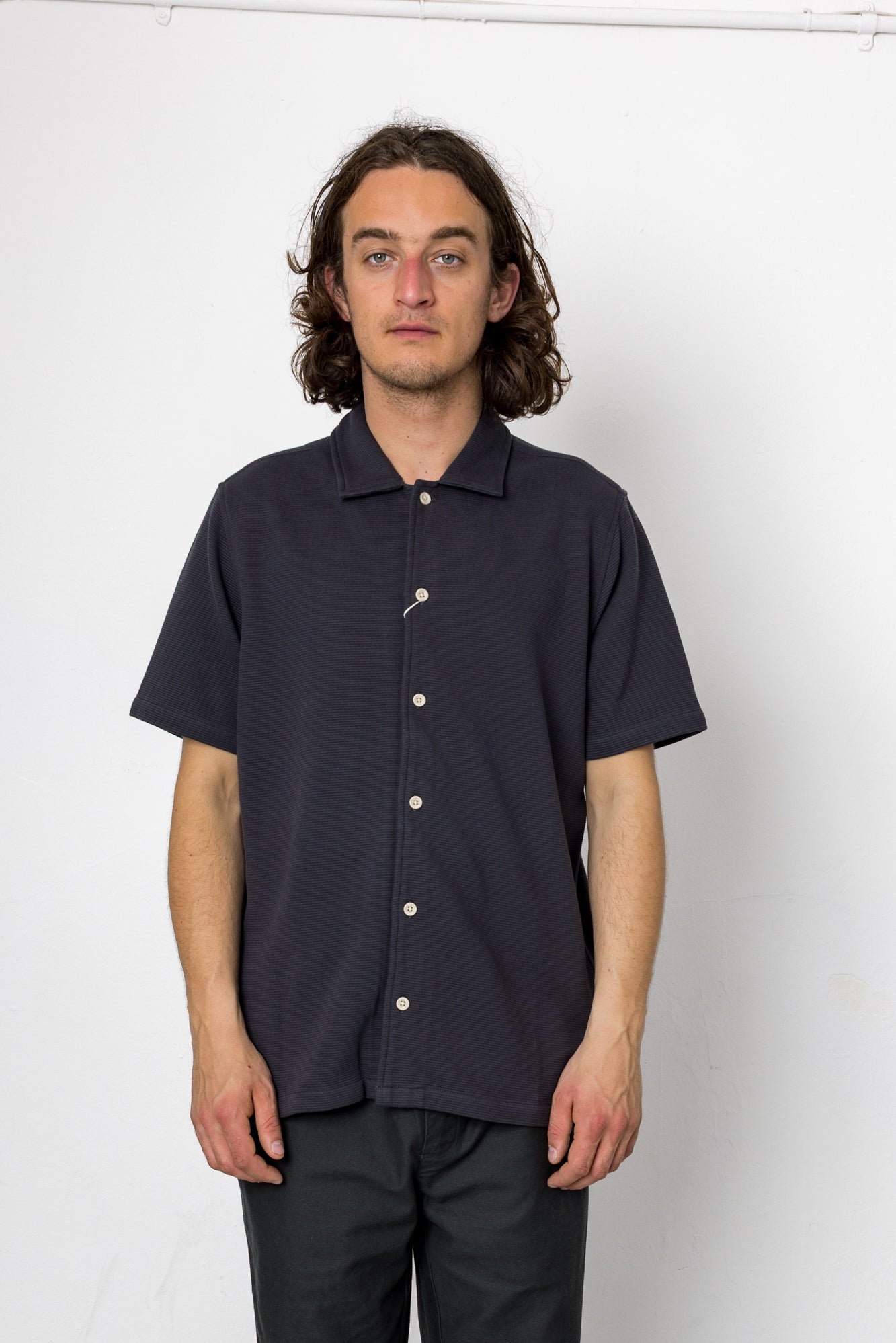 Man wearing a navy short-sleeve button-up shirt against a white background