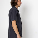 Man wearing a dark blue t-shirt and black pants against a white background