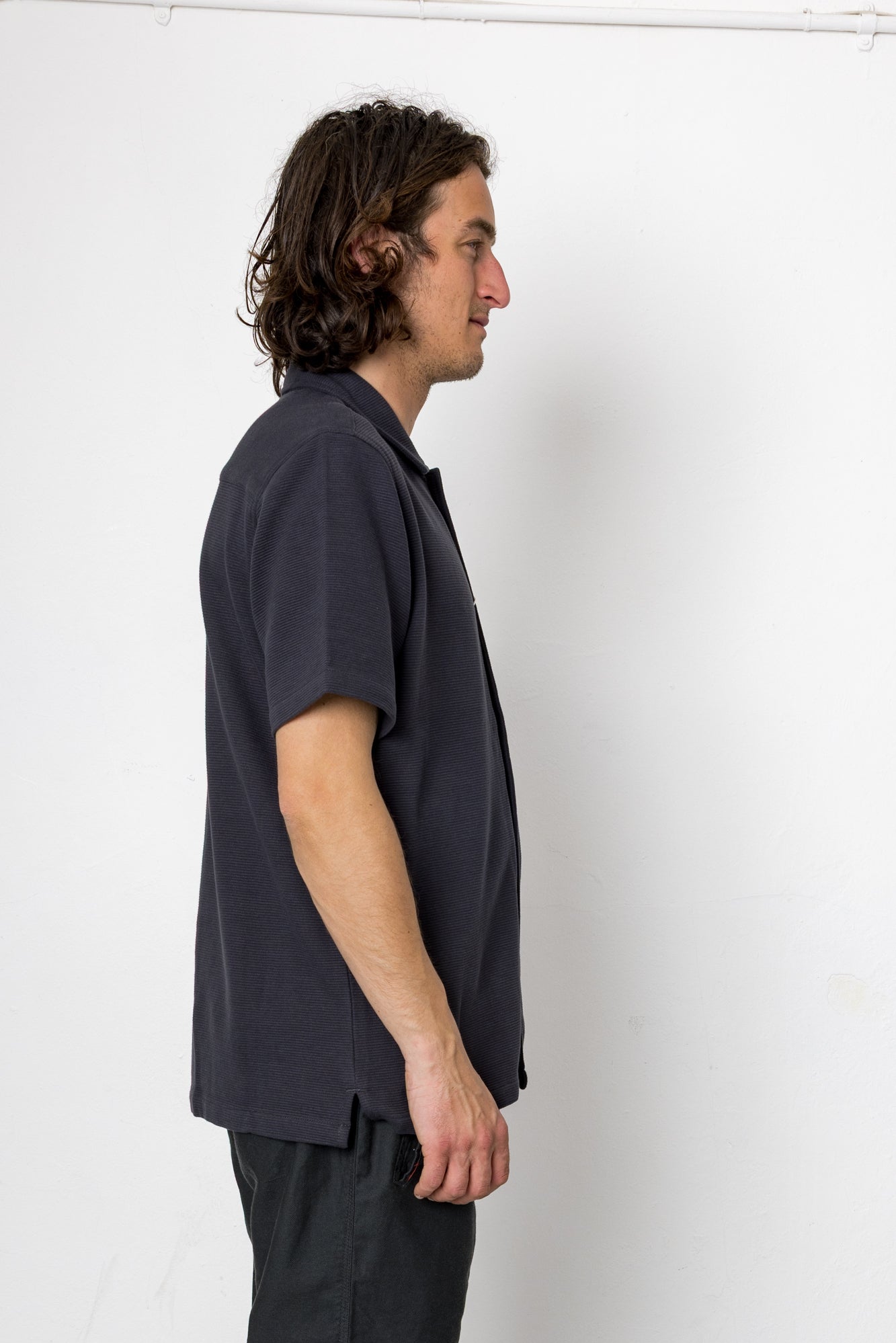 Man wearing a dark blue t-shirt and black pants against a white background