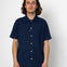 Man wearing a navy blue short-sleeve shirt with white buttons against a white background