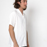 Man wearing a white pleated shirt against a plain background