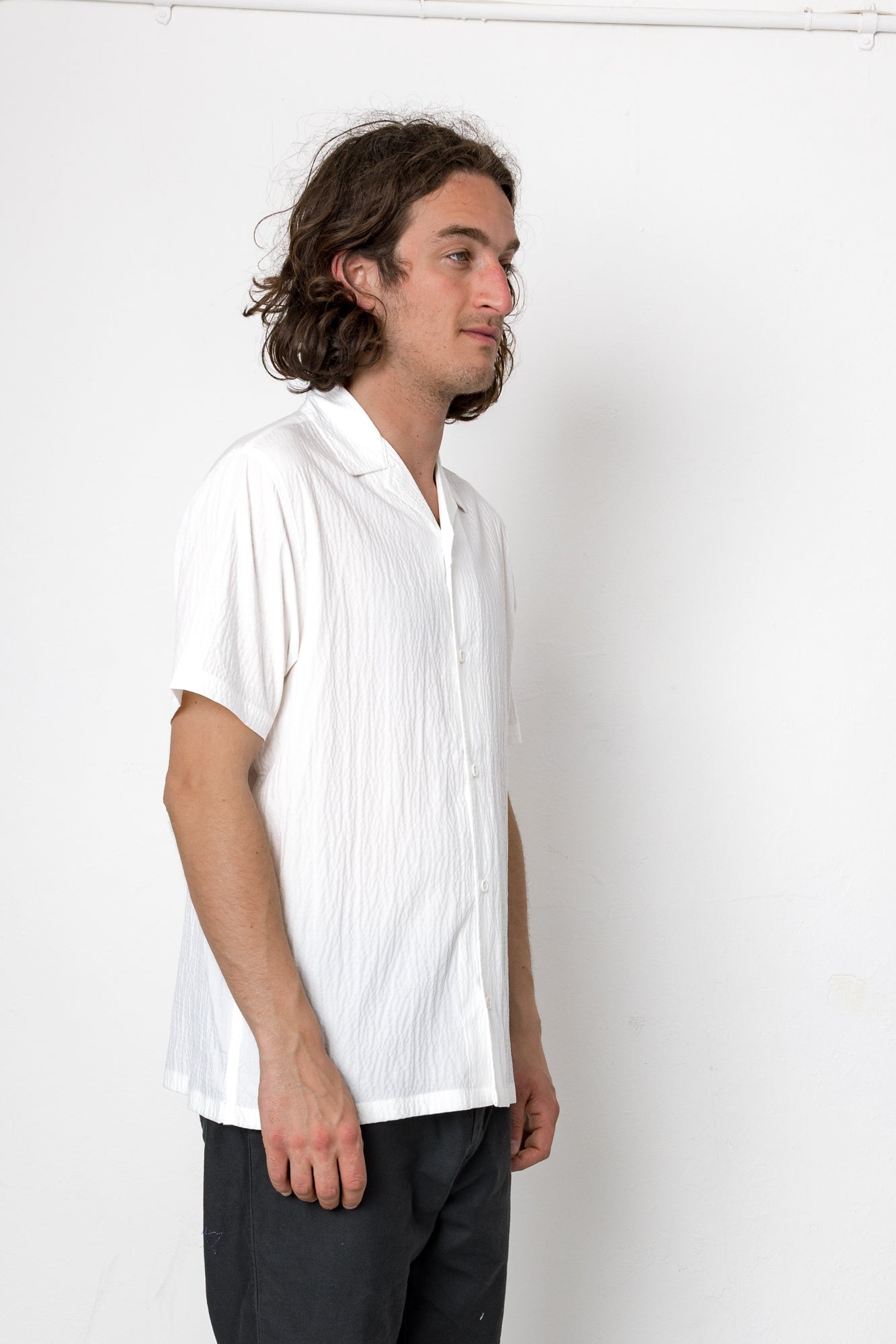 Man wearing a white pleated shirt against a plain background