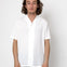 Man wearing a white shirt against a plain background