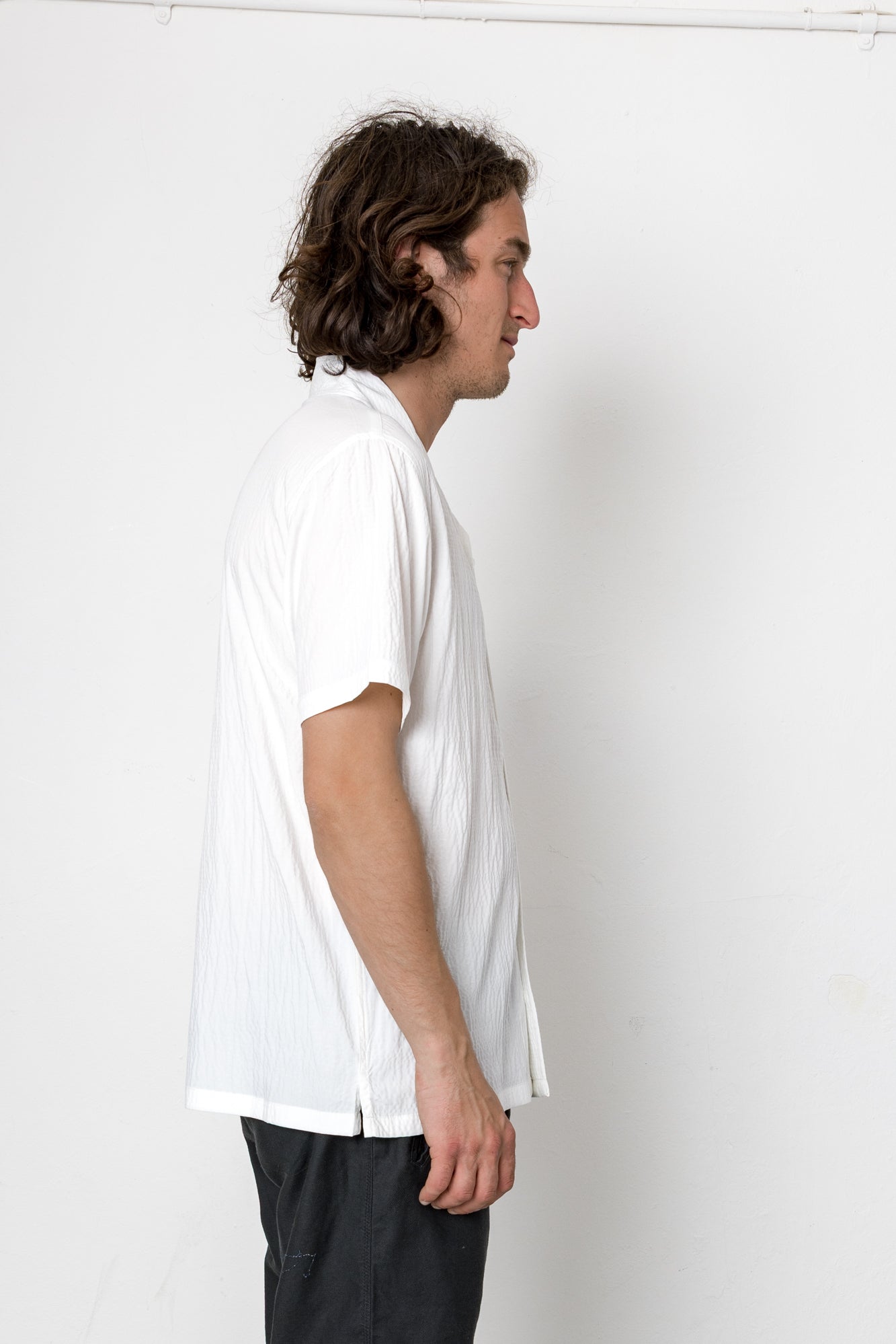 Person wearing a white t-shirt and black pants against a white background