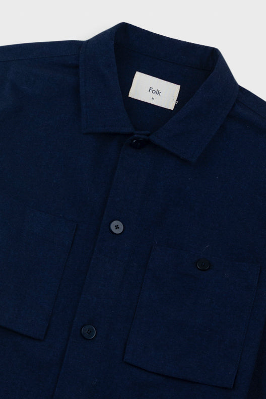 Navy overshirt with a visible brand label on a light gray background
