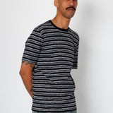 Man wearing a black and gray striped t-shirt and a black cap with a logo on a white background