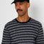 Man wearing a black and white striped t-shirt and a black cap with a small logo on a plain background