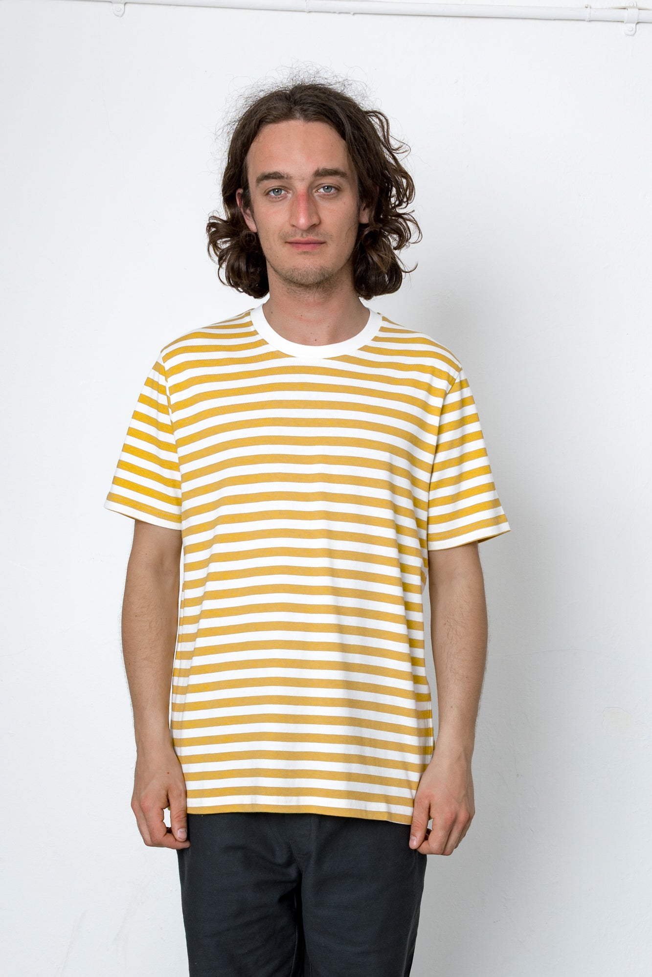 Person wearing a yellow and white striped t-shirt against a white background
