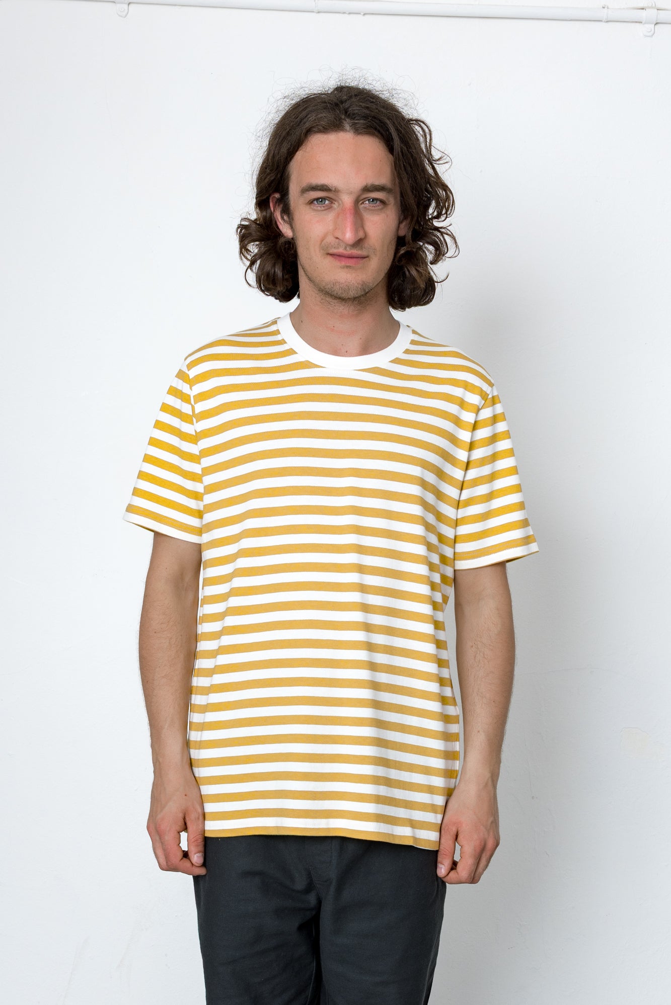 Man wearing a yellow and white striped t-shirt against a white background
