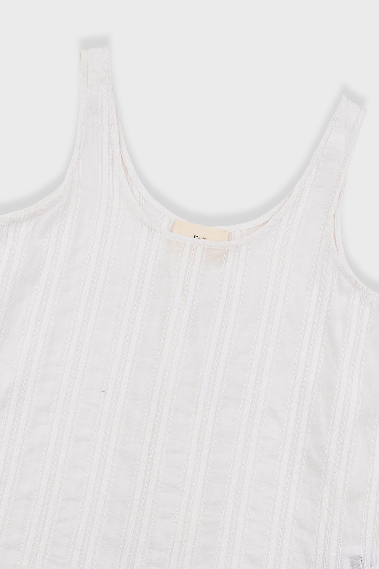 White ribbed tank top with a brand label on a white background