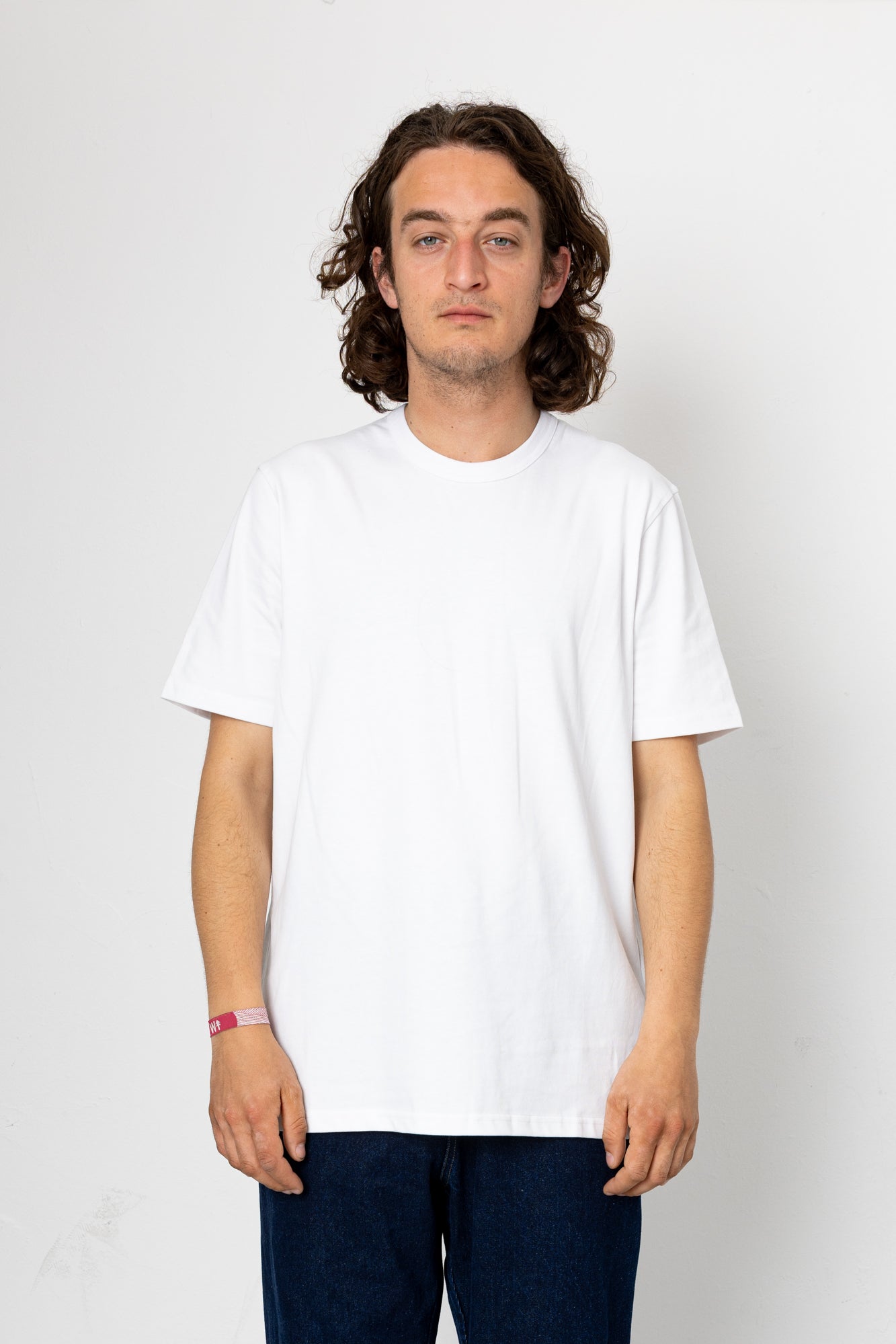 Man wearing a plain white t-shirt against a white background