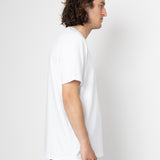Man wearing a plain white t-shirt and dark jeans against a white background
