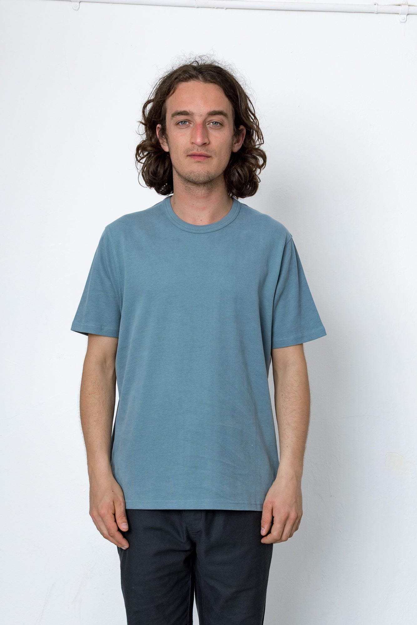 Person wearing light blue t-shirt and dark trousers