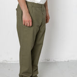 Person wearing olive green pants and black shoes on a white background