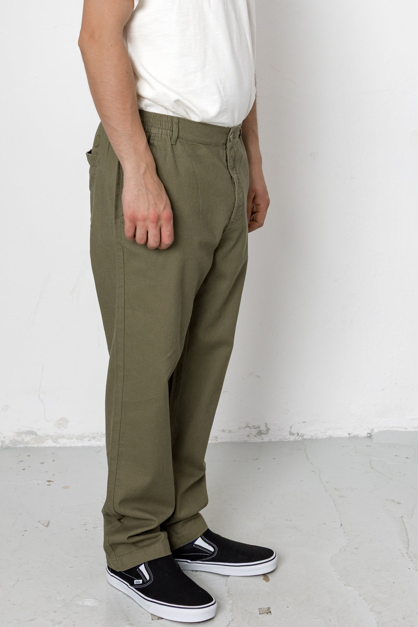 Person wearing olive green pants and black shoes on a white background