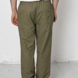 Person wearing olive green pants and a white shirt against a plain background
