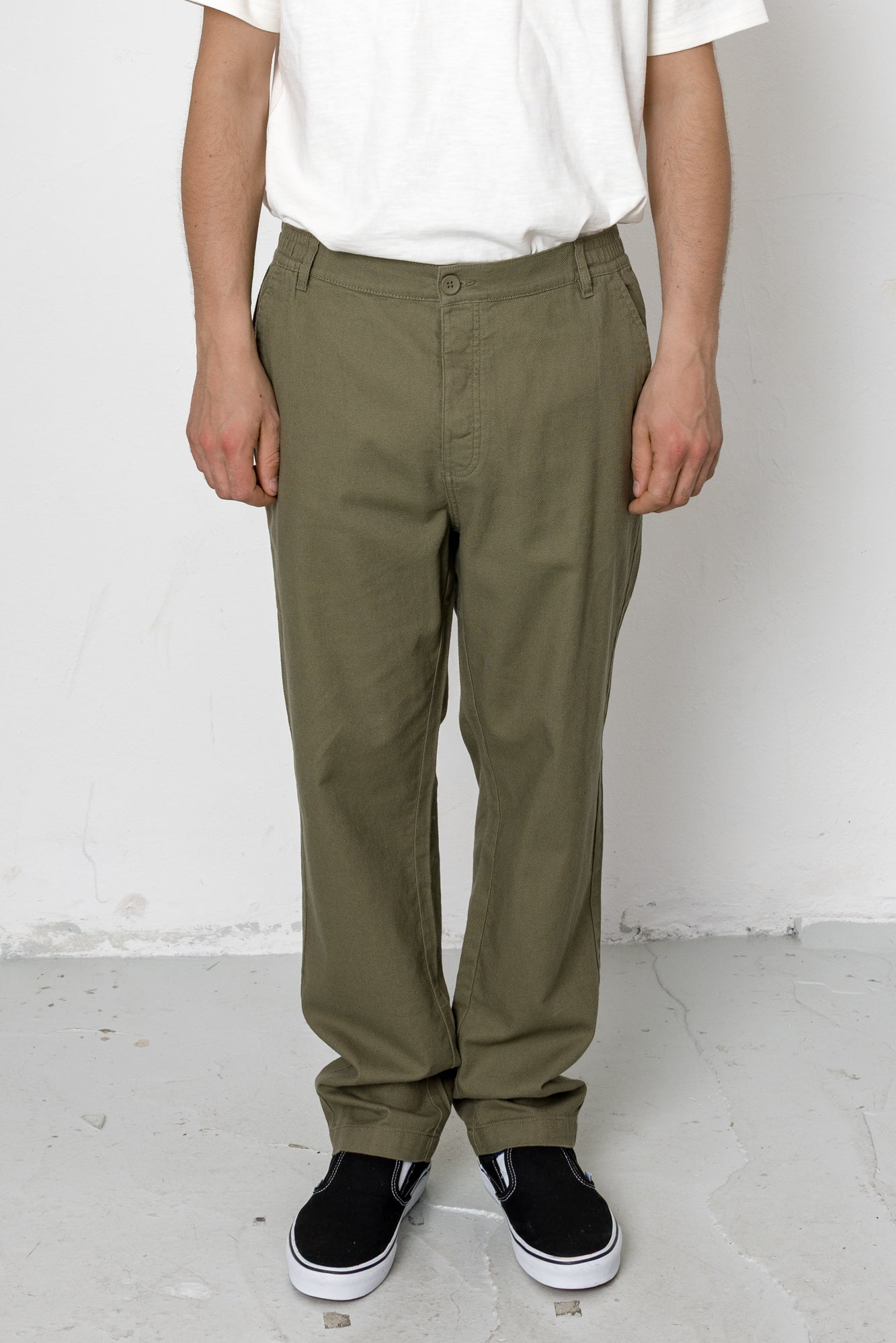 Person wearing olive green pants and black shoes against a white background