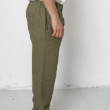 Person wearing olive green pants and black shoes against a white background