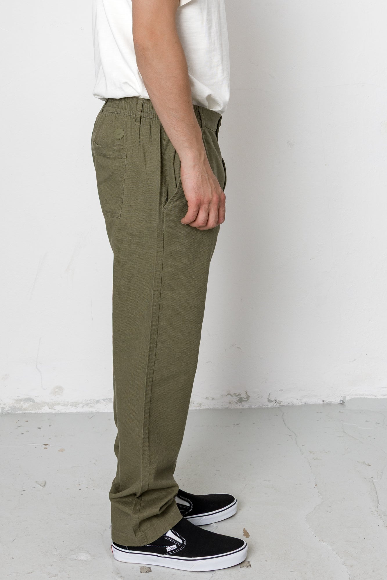 Person wearing olive green pants and black shoes against a white background